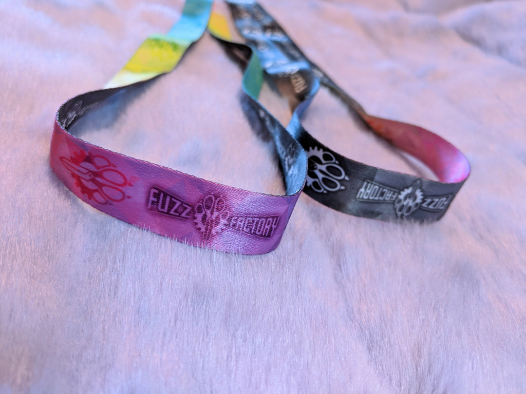 Two colorful wristbands with 'Fuzz Factory' branding on a light background