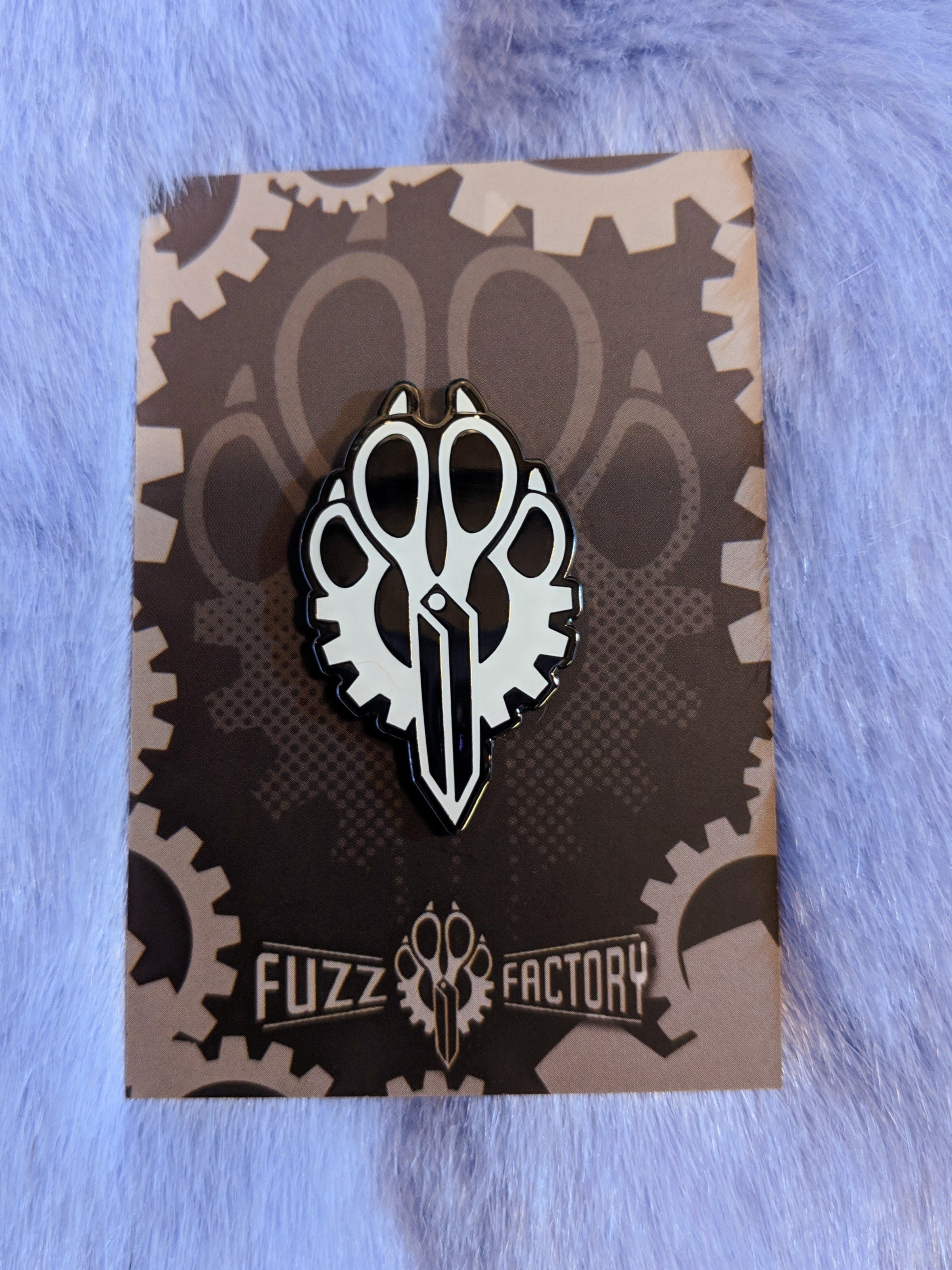 Pin with scissors design on a grey card with 'Fuzz Factory' branding, against a textured blue background.
