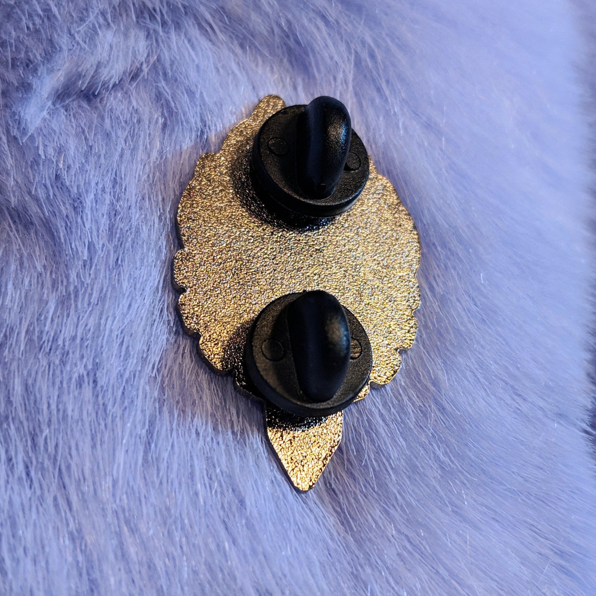 Silver pin back with black rubberized pin covers on a fur surface